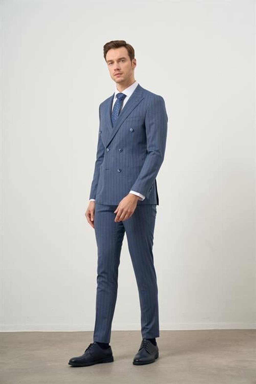 Стильный мужской костюм с узким силуэтом, темно-синего цвета, с острым воротником и двубортным дизайном, идеален для особых случаев