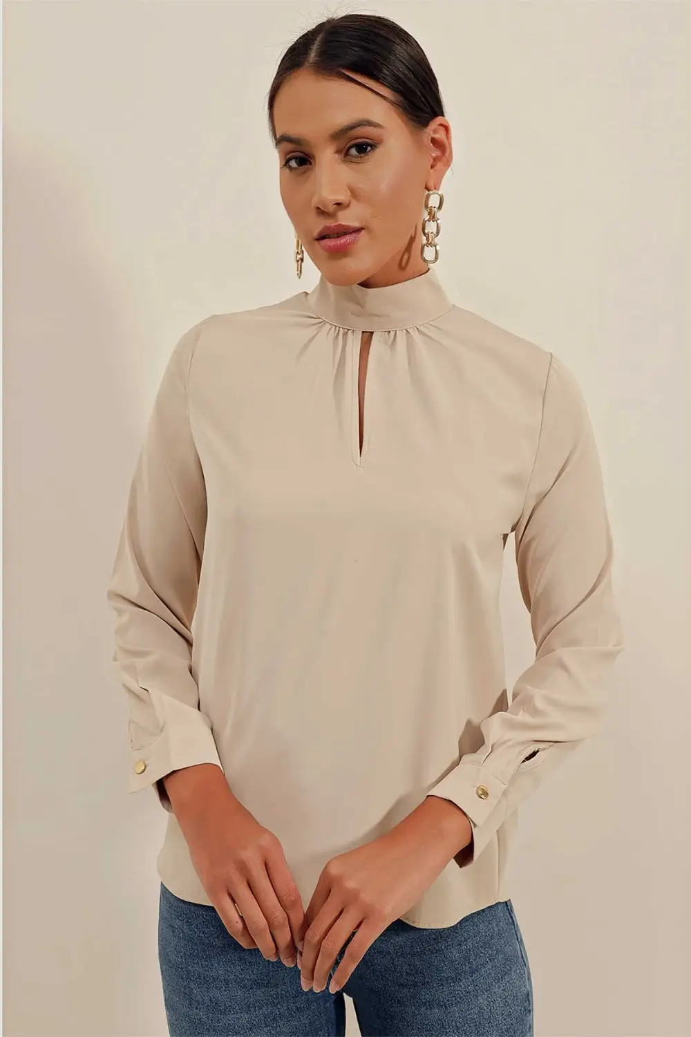 Жіноча блуза бежевого кольору з віконними деталями, довгими рукавами та коміром з гудзиками